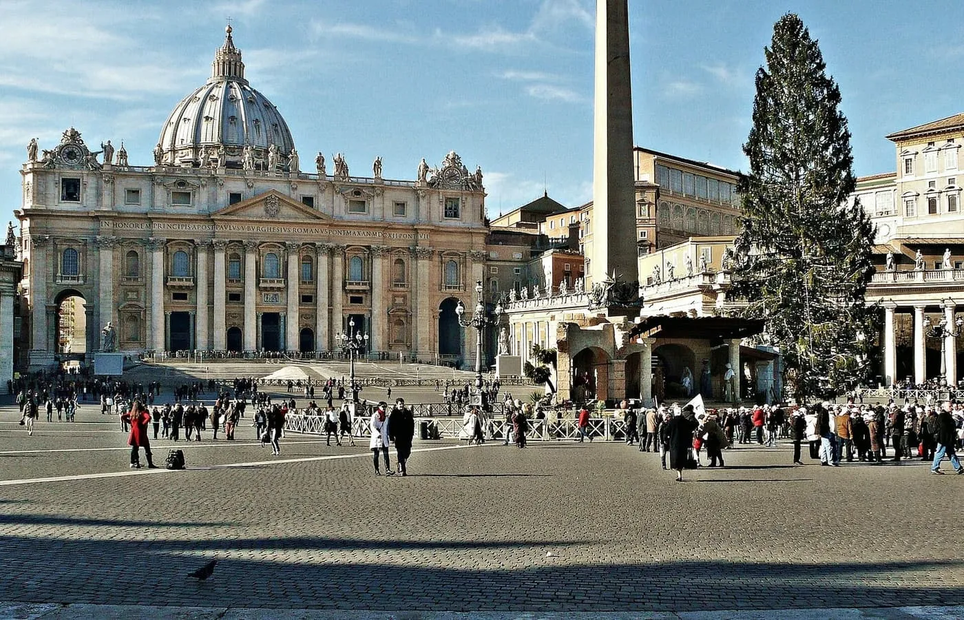 A tall Christmas tree and the nativity scene in St Peter's Square, with the obelisk and the basilica's facade behind
